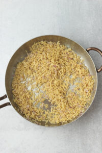 The orzo has been added to the frying pan.