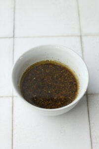 All of the dressing ingredients have been whisked in a small grey bowl.