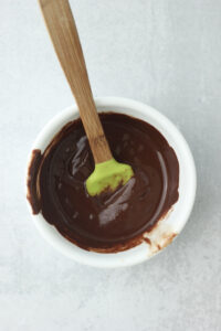 The chocolate and coconut oil have been melted in a small white bowl.