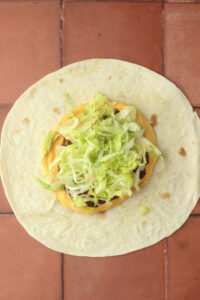 The lettuce has been added to the crunchwrap.