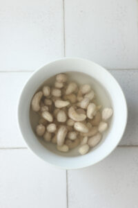 The cashews are soaking in a bowl of water to soften.