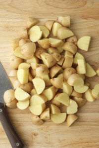 The potatoes have been chopped on a butting board.