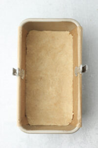 The dough has been pressed into the bottom of the bread pan in an even layer and is ready to bake.