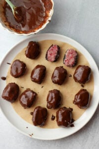 The dates have been dipped into melted chocolate and placec on a plate.