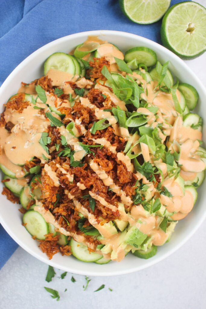 Crispy rice cucumber salad with creamy Thai dressing in a white salad bowl.