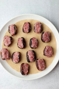 The dates have been stuffed with the raspberry coconut filling and are on a large white plate.