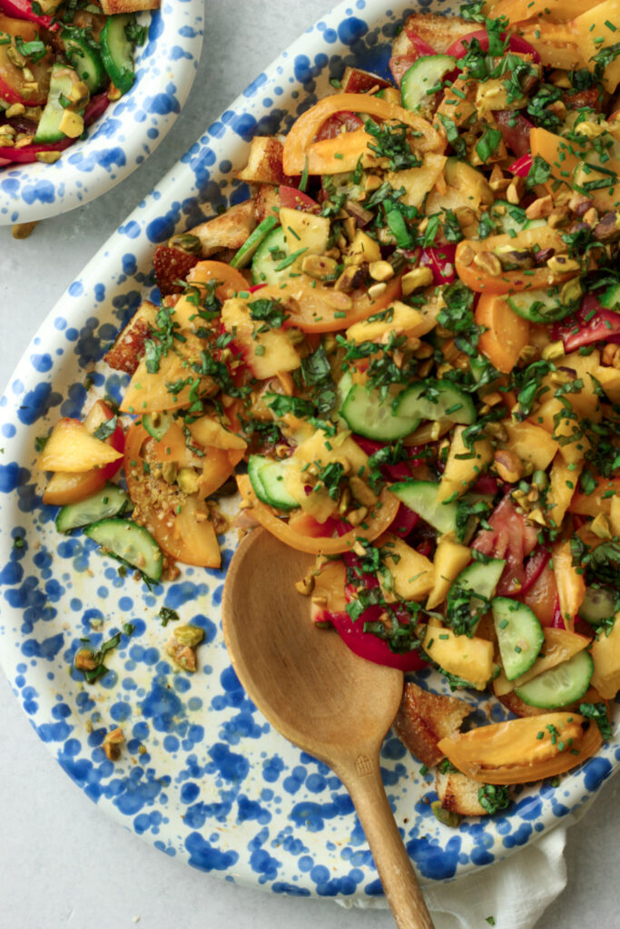 Vegan summer panzanella salad with heirloom tomatoes, peaches, cucumbers, basil, toasted pistachios, and toasted sourdough bread.