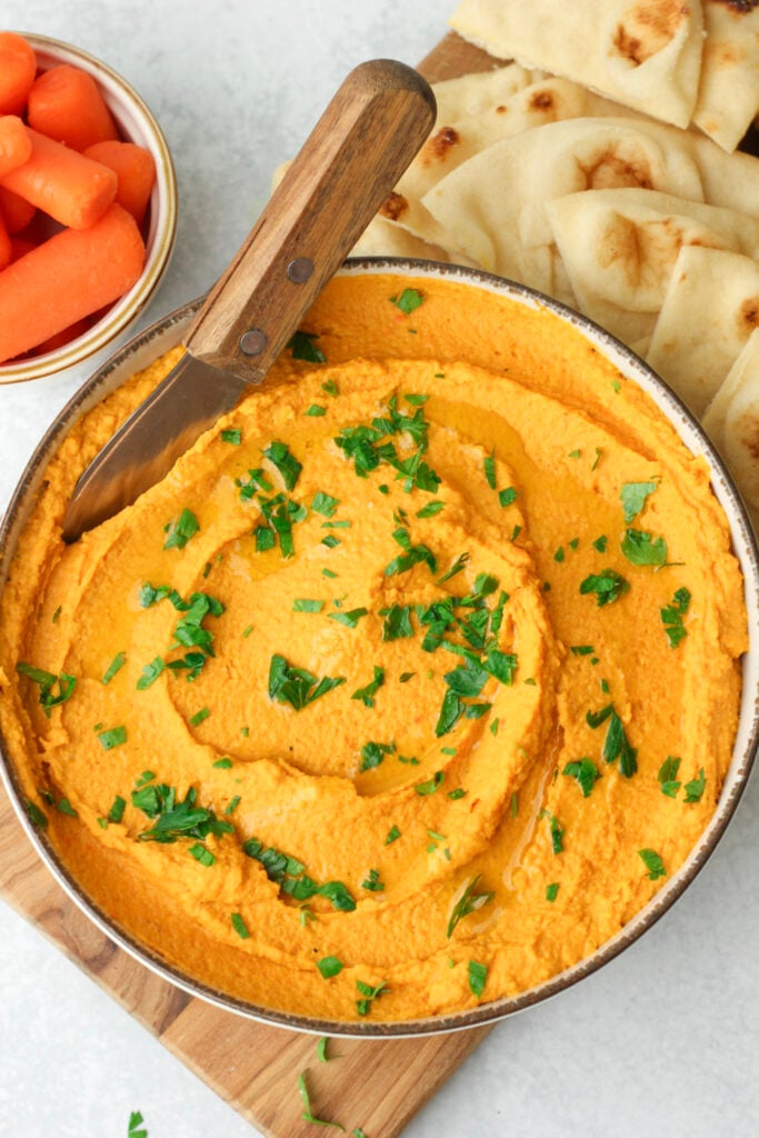 The carrot and garlic hummus is in a bowl and ready to enjoy.