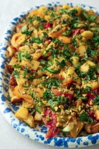 The chives, basil, peaches, and pistachios have been added, and now the salad is ready to serve.