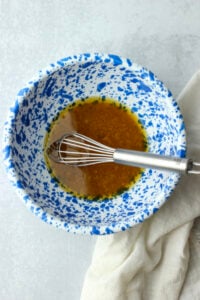The red wine vinaigrette has been whisked in a blue bowl.