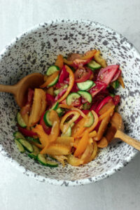 The tomatoes and cucumber slices are in a large bowl, marinating in the dressing.