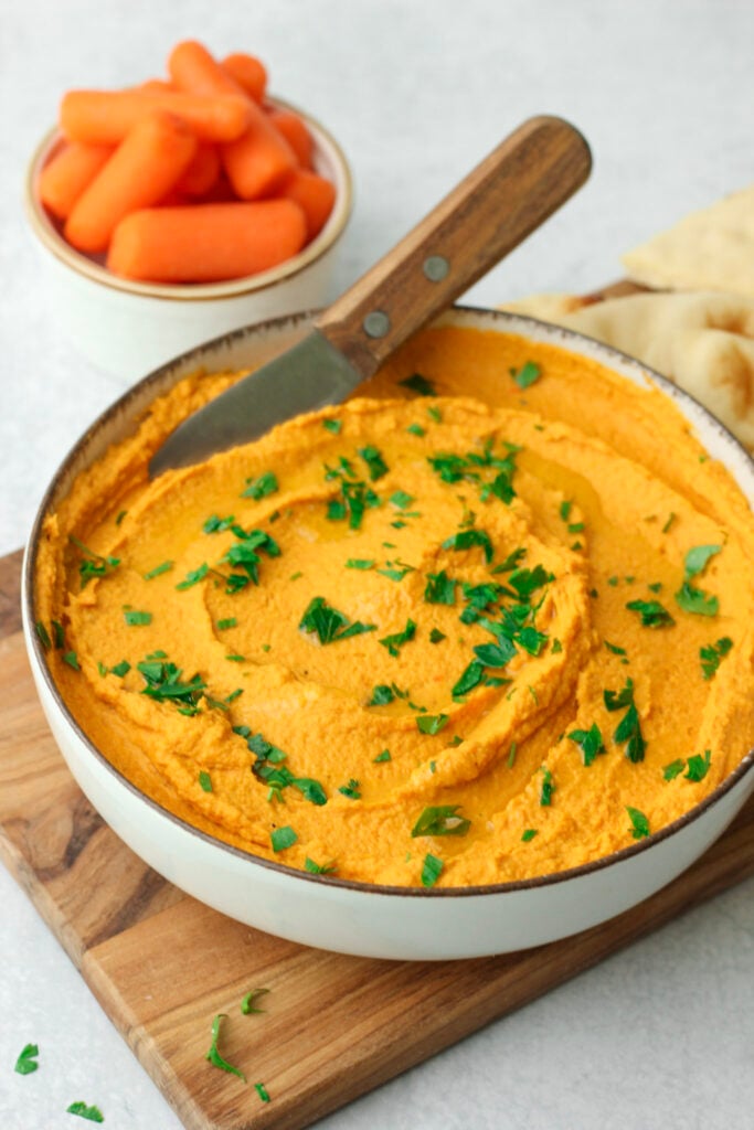 The carrot and garlic hummus has been topped with minced parsley.
