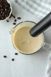 The coconut cream has been frothed in a large glass cup.