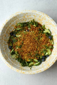 The remaining ingredients have been added to the kale in the yellow bowl.