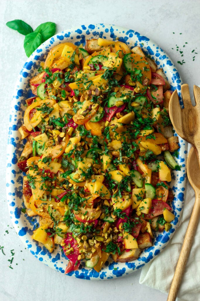 This summer heirloom tomato and peach panzanella salad is on a platter and ready to serve.