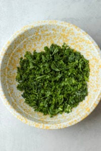 The kale leaves have been massaged in a large yellow bowl.