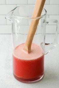 The lime juice, maple syrup, and bottle of wine have been added to the pitcher and stirred.