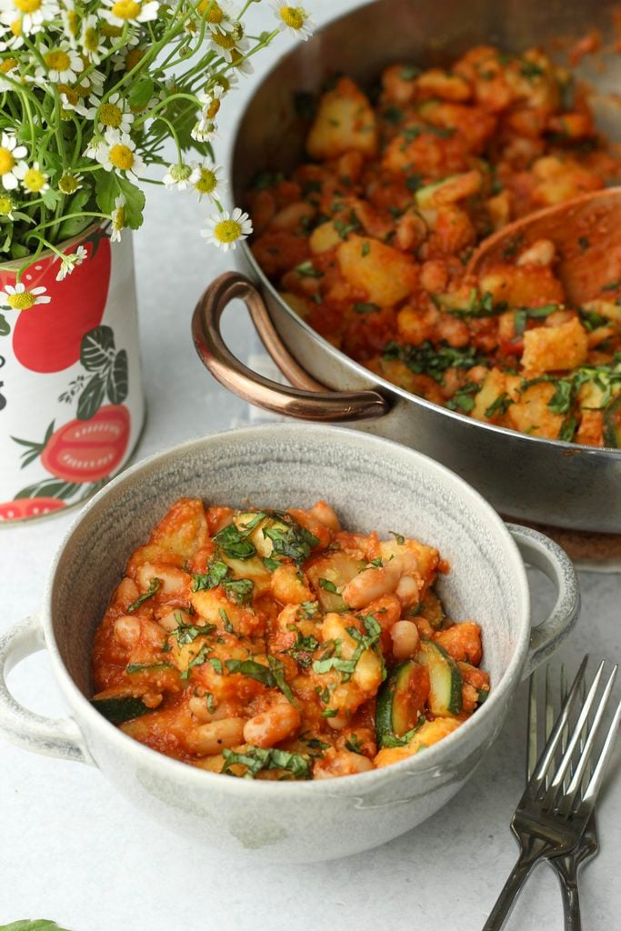 One serving is in a small grey bowl and topped with minced basil.