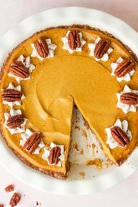 The whipped cream swirls and candied pecans have been added to the finished creamy pumpkin pie.