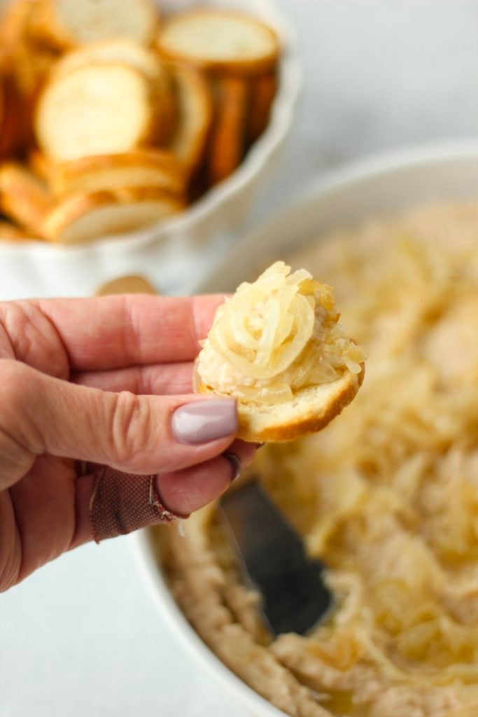 The bean dip has deen spread onto a cracker that is being held.
