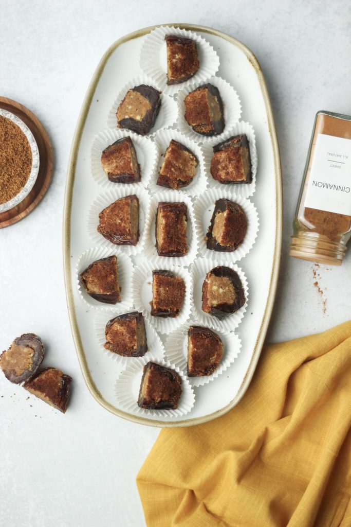Cinnamon sugar stuffed dates have been cut into halves and placed on a tan platter.
