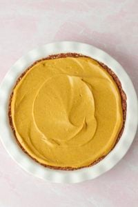 The pumpkin filling has been poured over the crust and spread into a smooth, even layer.