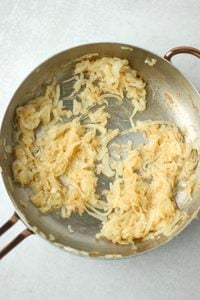 The onions have been caramelized in a large frying pan.
