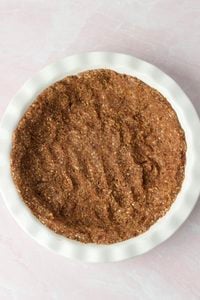 The crust mixture has been pressed into the bottom of a pie plate. 