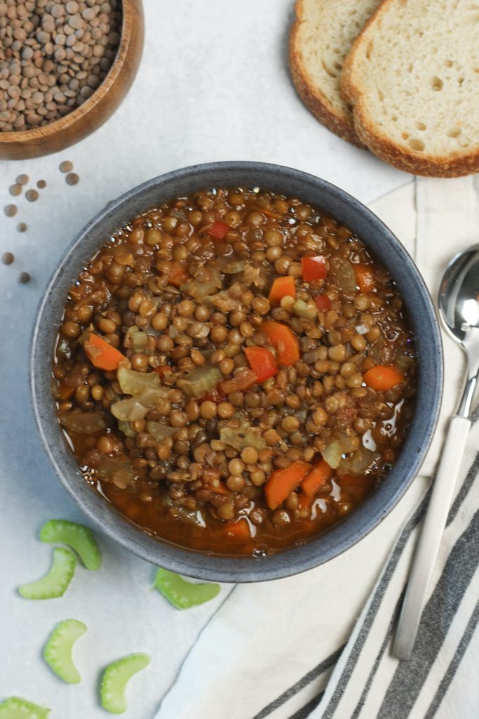 A bowl of warm vegan lentil soup with a spoon.