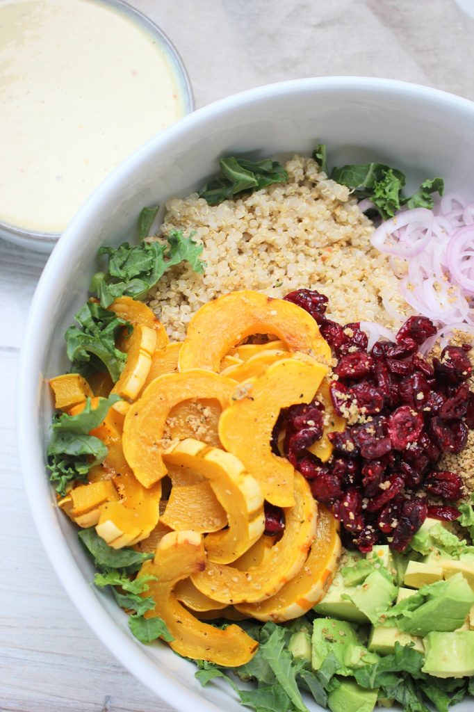 The vegan Thanksgiving salad is in a large white bowl with the dressing on the side.